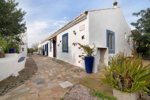 a white building with blue doors and potted plants at Quinta do Mestre - Casa Do Mar in Tavira