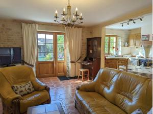 a living room with two leather couches and a kitchen at Le Clos Pierreslogis in Theil-Rabier