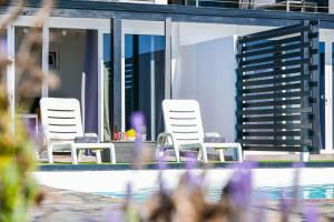 two white chairs sitting next to a swimming pool at Casa Amanecer 3 in Mácher