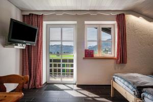 a room with two windows and a television and a bed at Appartement Braun 1 in Bolsterlang