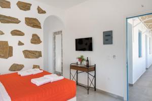 a bedroom with an orange bed and a wall with rocks at Politimis Studio N4 in Amorgos