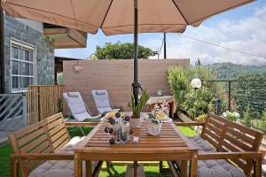a wooden table with an umbrella in a garden at La Casa di Giosy in Cairo Montenotte