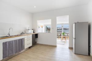 a white kitchen with a refrigerator and a table at Beach House el Poris 2 in Poris de Abona