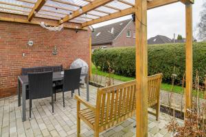 a patio with a table and chairs and a wooden pergola at Ferienwohnung Utkiek in Ihlow