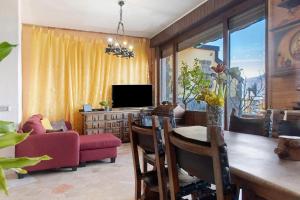 a living room with a dining table and a tv at L'attico Con Terrazza Vista Lago in Laveno-Mombello