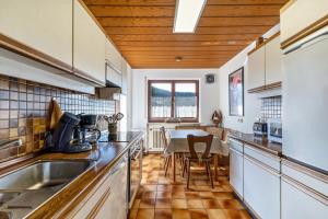 a kitchen with wooden ceilings and a table with chairs at Hirschturmblick in Zell am Harmersbach