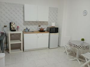 a kitchen with white cabinets and a microwave and a table at Mini appartamento a Marcianise in Marcianise +10 photos