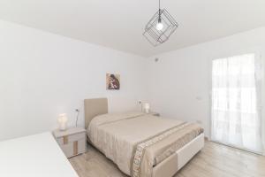 a white bedroom with a bed and a window at Casa Virgi vista mare in Budoni