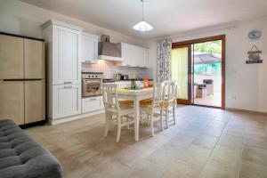 a kitchen with white cabinets and a table and chairs at Soleluna apartment in Castelsardo