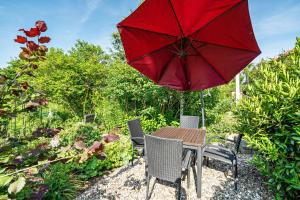 a table and chairs with a red umbrella at Ferienwohnung 1 Schulze in Neustrelitz