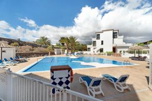 a swimming pool with chairs and a house at Blue Dream Pebble Beach in San Miguel de Abona