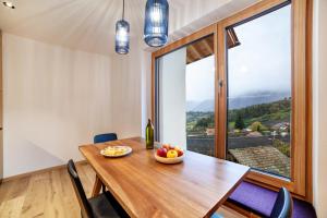 a dining room with a wooden table and a large window at Huetterhof Apartement Winter in Caines