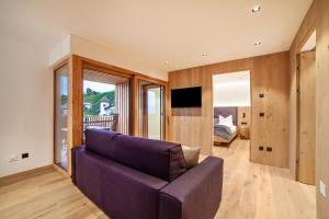 a living room with a purple couch and a tv at Huetterhof Apartement Winter in Caines