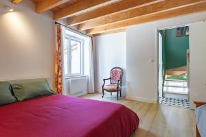 a bedroom with a bed and a chair and a window at L'Arche aux Peyruches in Assieu