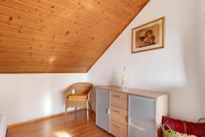 a room with a wooden ceiling with a chair and a dresser at Ferienwohnung Schöne Aussicht in Gemmrigheim