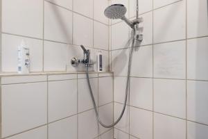 a shower with a shower head in a white tiled bathroom at Ferienwohnung Schöne Aussicht in Gemmrigheim +21 photos
