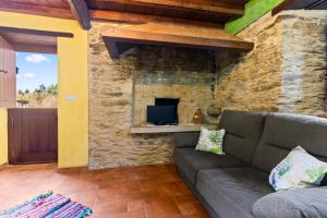 a living room with a couch and a stone fireplace at Eiron in O Porto de Espasante