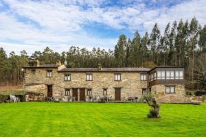 an old stone house with a large grass field at Eiron in O Porto de Espasante