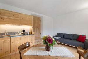 a living room with a table with a vase of flowers at Ansitz Baumannhof Apt Mitte in Falzes +13 photos