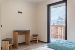 a bedroom with a bed and a desk and a balcony at Villa Lara Zirbe in Castelrotto