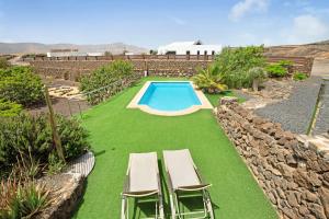 a swimming pool with two lawn chairs and a table at Tayu Eco Villa in Villaverde