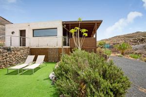 a house with a green lawn and two chairs at Tayu Eco Villa in Villaverde