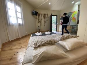 a man walking in a room with a large bed at YMCA Camp Alambre in Azeitao +3 photos