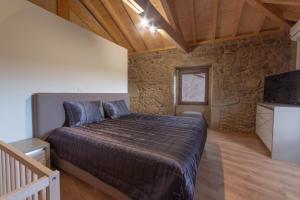 a bedroom with a large bed in a stone wall at Villae Carreiro in Palmeira +26 photos