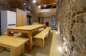 a room with wooden tables and benches and a stone wall at Villae Carreiro in Palmeira