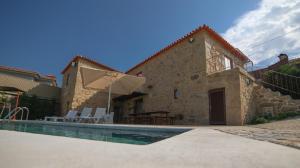 a house with a swimming pool in front of a building at Villae Carreiro in Palmeira