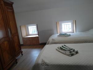 a bedroom with two beds and a dresser and two windows at La Clef in Saint-Julien-Molin-Molette