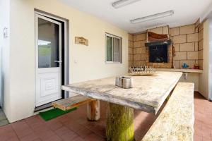 a kitchen with a wooden table and a fireplace at Casinha do Monte in Achadinha