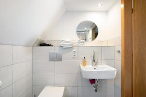 a white bathroom with a sink and a mirror at An der Rehkoppel in Boren +15 photos