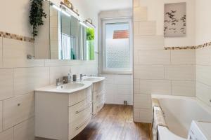 a white bathroom with two sinks and a tub and a window at Ferienhaus Optikstadt Rathenow in Rathenow +17 photos