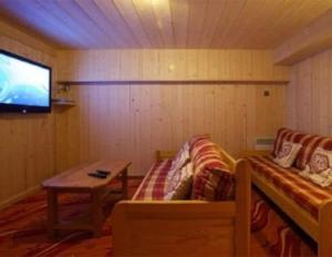 a room with a couch and a table and a tv at Chalet Myrtille in Morzine +5 photos