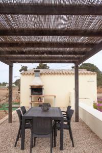 a black table and chairs under a wooden pergola at Vivendes Adelina - Escapada Formentera in Es Pujols
