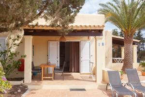 a house with chairs and a table and a palm tree at Vivendes Adelina - Escapada Formentera in Es Pujols