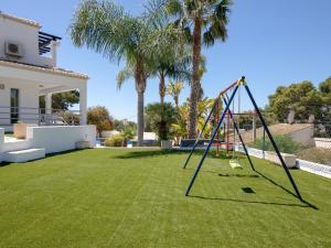 a swing in a yard with palm trees at Fustera in Benissa