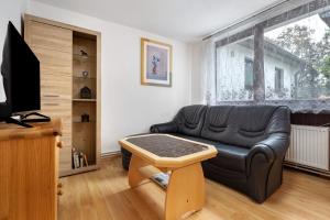 a living room with a black leather couch and a table at Gemütliche Wohnung Buchholz i d N in Buchholz in der Nordheide