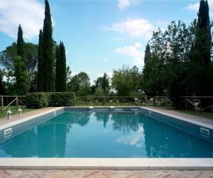 una piscina en un patio con árboles en Castello di San Fabiano, en Monteroni dʼArbia