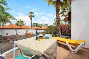a table and chairs on a patio with palm trees at La Villa La Palma- 1 dormitorio A in Los Barros