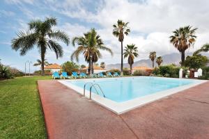 a swimming pool with chairs and palm trees at La Villa La Palma- 1 dormitorio A in Los Barros