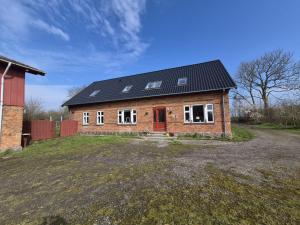 a brick house with a black roof on a field at Søndergaarden in Øster Ulslev