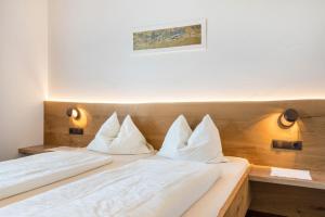 a bed with white sheets and pillows on it at Haus Rosengarten Apt B in Terlano