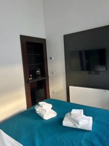 two towels on a blue bed with a television at Luxury Room in Bari +2 photos