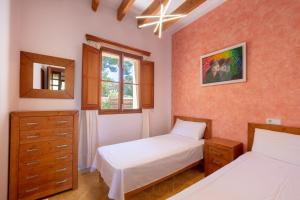 a bedroom with two beds and a dresser and a window at Villa Rosa in Cala Santanyi