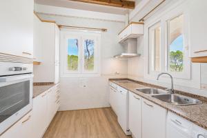 a kitchen with white cabinets and a sink at Villa Rosa in Cala Santanyi