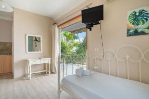 a bedroom with a bed and a balcony with a television at Giorgio studios-apartments 1 in Nikiana