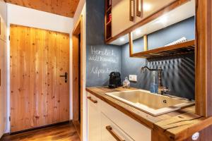 a kitchen with a sink and a wooden wall at Chalet Alpenherz in Inzell +17 photos