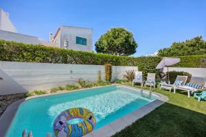 a swimming pool in a yard with two chairs and an umbrella at V-Blue in Alvor